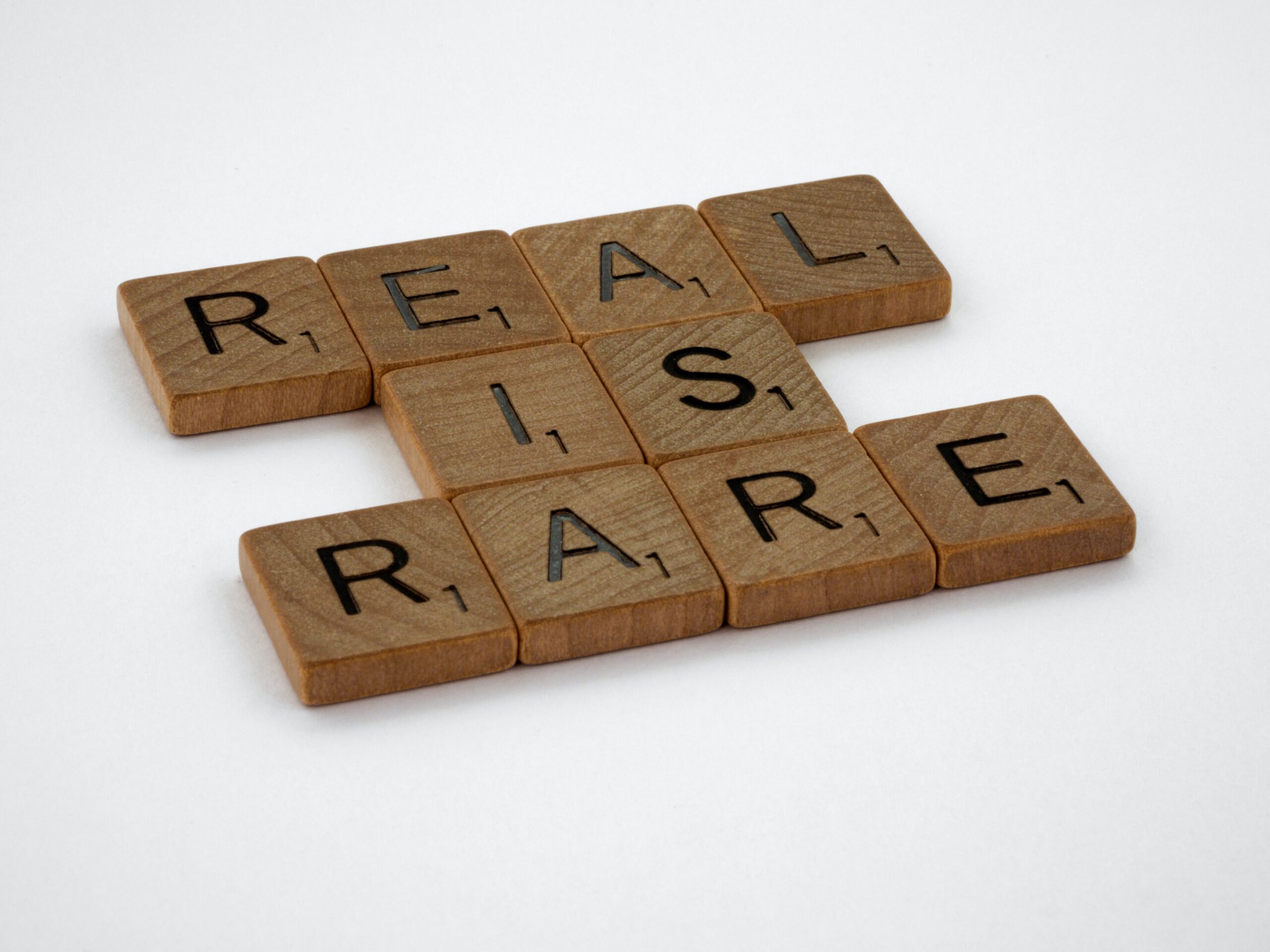 A group of tiles with letters on them. The are arranged to read "REAL IS RARE"